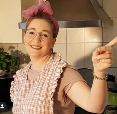 Sängerin Betti Konfetti mit pinker Haarschleife und Küchenschür2020 zu Hause während der Coronazeit.