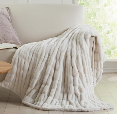 a white couch with a white plush blanket on it