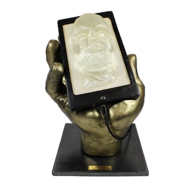 Lode sculpture intitulée Narcisse représentant une main tenant un téléphone avec un visage qui sort de l'écran