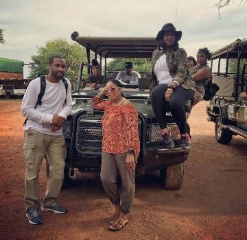 A group of tourists posing by a safari vehicle on a guided African wildlife tour.