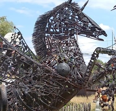 A large scrap metal sculpture of a winged pegasus horse made from recycled iron parts.
