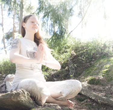 a woman meditating on a rock in a forest