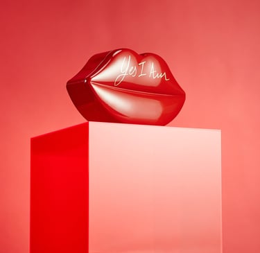 Product Photography of a bold lips-shaped perfume bottle on a vibrant red backdrop, using glossy tex