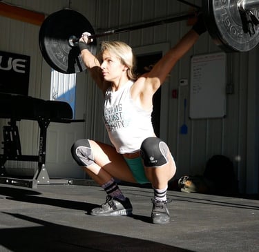 a woman is squatting on a barbell