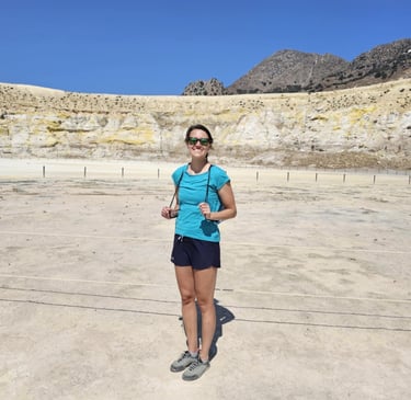 a woman in a blue shirt and sunglasses standing in a desert