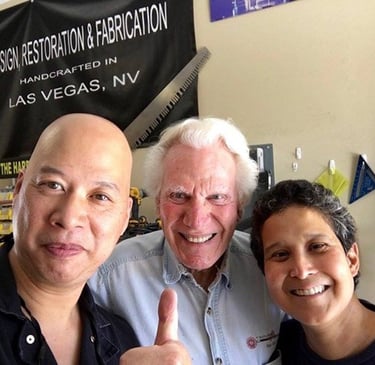 Three smiling men posing in a Las Vegas custom fabrication and restoration workshop.