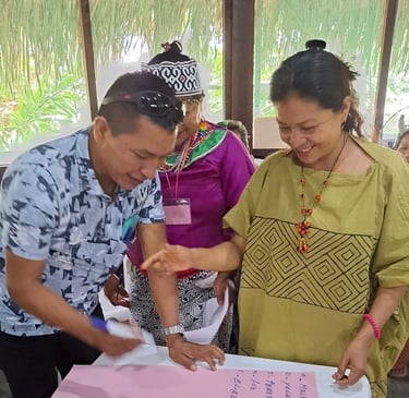 Indigenous community members in traditional attire collaborate on a project during a workshop.