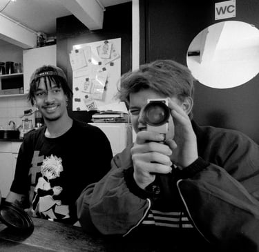 Youth looking through a Super8 film camera with his friend watching.