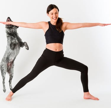 a woman in a black top and leggings and a dog standing in front