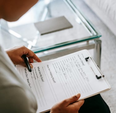 a woman is holding a pen and writing on a notepad