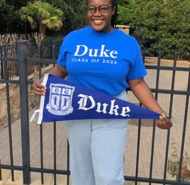 Black female posing with a Duke University banner
