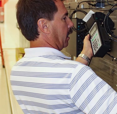A professional network technician uses a handheld testing device to certify voice and data connections