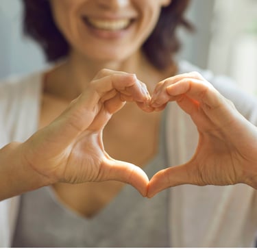 Mujer sonriendo haciendo con sus manos la forma de un corazón