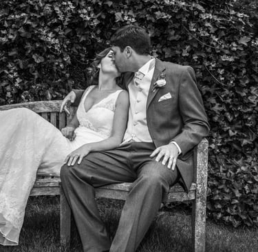 Husband kisses wife on a wooden bench