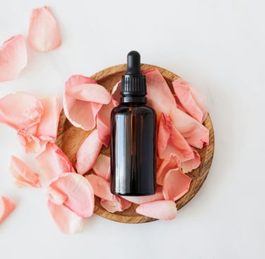a bottle of essential oils with pink flower petals