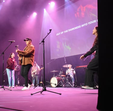 A band leading worship on stage, with guitars, drums, and singers