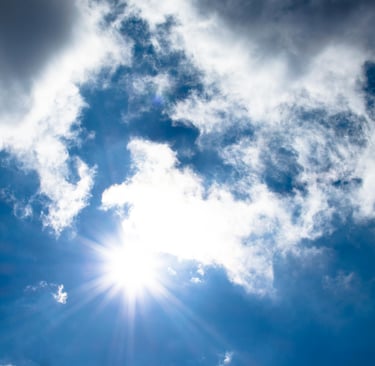 a plane flying through the sky with a sun shining through the clouds