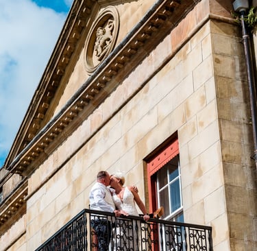 a bride and groom kissing on a balcony balcony