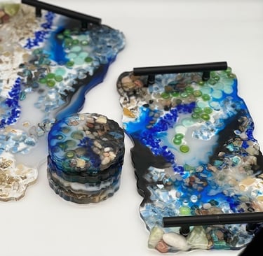 two trays with black handles, incorporating rock, shell, and glass design elements