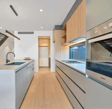Modern kitchen with sleek cabinetry, built-in appliances, and under-stair sink area