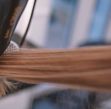 a woman is blow drying her hair in a salon