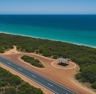 Aerial view of coastal highway with picnic shelter, side road, and turquoise Indian Ocean.