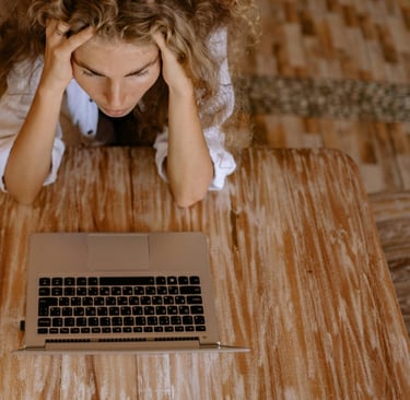 a woman sitting at a table with a laptop and a cell phone