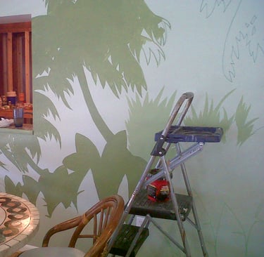 An interior mural underway with a ladder, paint bucket, rags, and tools in the kitchen.