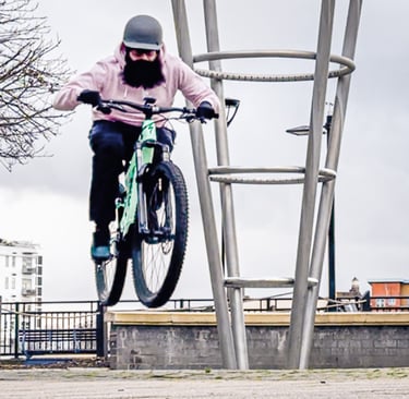 A bearded man in a helmet in mid-air during bike jump.