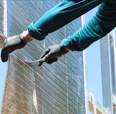 Person installing insulation on metal building