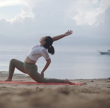 Woman stretching on a beach at sunrise, practicing active recovery with yoga to promote muscle flex