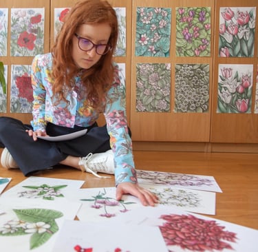 A Woman sat on the floor surrounded by botanical illustrations