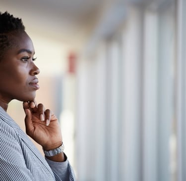 Una mujer afro con pendientes de perla y mirada pensativa