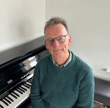 Photo of Steven with a piano behind him
