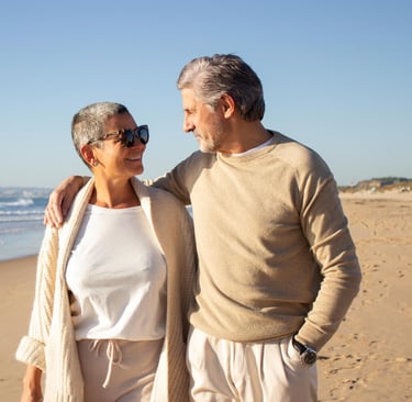 Happy retired expat couple on Murcia beach enjoying Spanish lifestyle with insurance protection