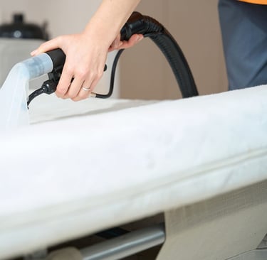 a person is cleaning a mattress with a vacuum
