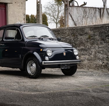 a fiat 500 parked in front of a red garage door