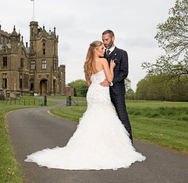 bride and groom stood in a dramatic pose into front go a grand castle