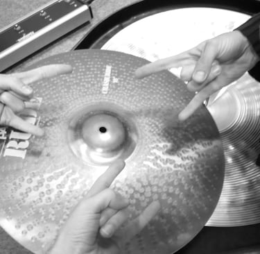 3 mains faisant le signe du métal au-dessus d'une cymbale