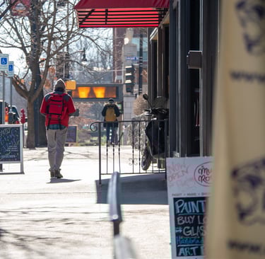 Man walking on a sidewalk downtown past business and sandwich signs