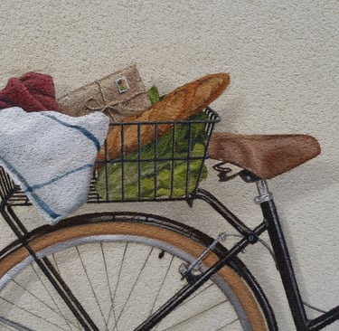 Détails d'un panier de vélo peint dans une fresque en trompe-l'oeil. Une baguette, une enveloppe.