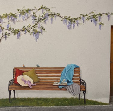 Fresque en trompe-l'oeil sur façade. Un banc posé sur l'herbe, des oiseaux, un livre et une glycine.