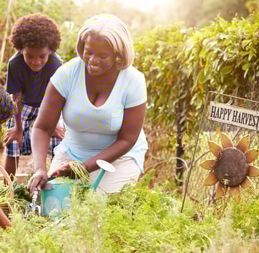 Una mujer afro con dos crios en un jardin