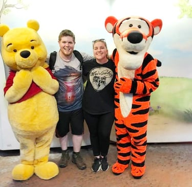 Sarah Brewer pictured with her husband, along with Winnie the Pooh and Tigger.