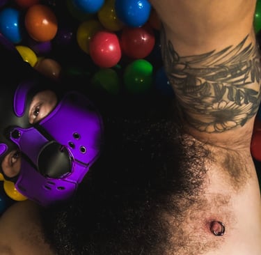 Man in pup mask lying in a ball pit.