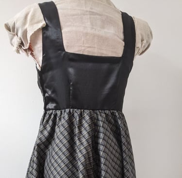 The back of a black/gold plaid and black satin flowy cocktail dress