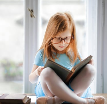 a young girl is sitting on a table with a book