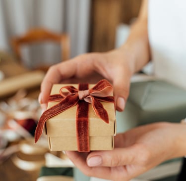 a person holding a small gift box with a red ribbon