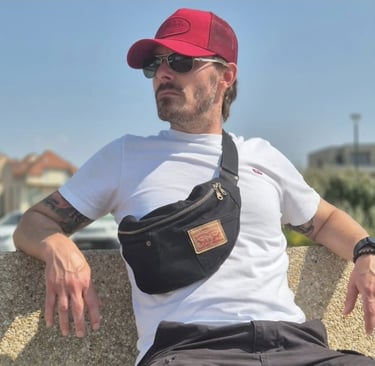 un homme assis portant un sac banane en jean noir recyclé en bandouillère