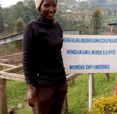 a woman standing in front of a sign that says, women"s coffee famers